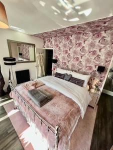 a bedroom with a large bed with roses wallpaper at Gamelin in Llangollen