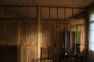 a room with a wooden wall with a refrigerator at Kipiani's guesthouse in Ambrolauri