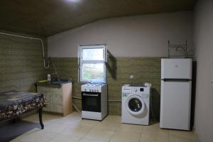 a kitchen with a washing machine and a refrigerator at Kipiani's guesthouse in Ambrolauri
