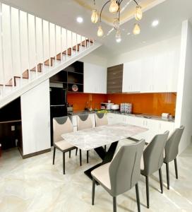een keuken met een tafel en stoelen en een trap bij Sunrise House in Hàm Tân