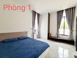 een slaapkamer met een blauw bed en ramen bij Sunrise House in Hàm Tân