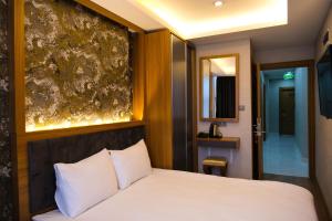 CALENBERG HOTEL في إسطنبول: غرفة نوم بسرير ابيض ولوحة على الحائط