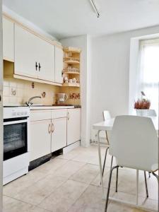 a kitchen with white cabinets and a table and a sink at Imperial museum apartment in London