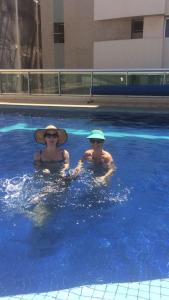 dos personas en una piscina en el agua en Miniduplex bem localizado, en Brasilia