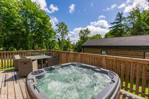 a hot tub on a deck with a wooden fence at Squirrel Lodge 41 with Hot Tub in Newton Stewart