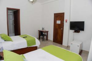 a hotel room with two beds and a flat screen tv at Hotel Castell in Guayaquil