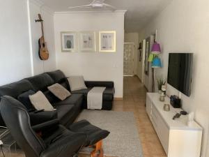 a living room with a black couch and a television at La Mar 2 bed 2 bath in sought after position FREE WIFI in Puerto de Santiago