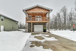 une maison en rondins avec un garage dans la neige dans l'établissement Lovely Elmira Cabin with Deck, 18 Mi to Gaylord, 