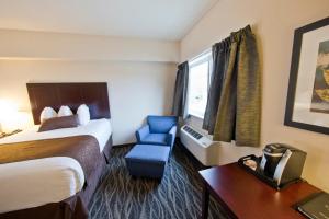 a hotel room with a bed and a blue chair at Cobblestone Inn & Suites -Clarinda in Clarinda