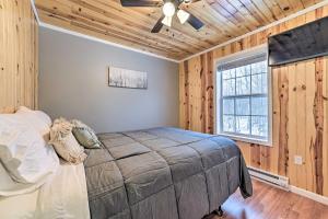 sypialnia z łóżkiem w pokoju z drewnianymi ścianami w obiekcie Lovely Elmira Cabin with Deck, 18 Mi to Gaylord 