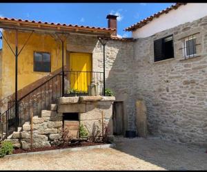 ein Steinhaus mit gelber Tür und Treppe in der Unterkunft Villa Candoso 