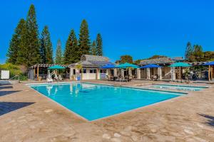 una piscina en un complejo con sombrillas azules en Greens At Waikoloa J101, en Waikoloa Village