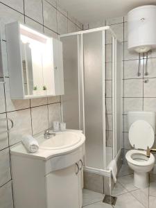a white bathroom with a toilet and a sink at Villa Sofija in Supetar
