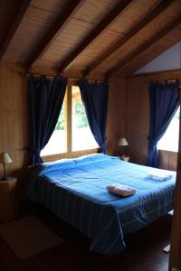 a bedroom with a blue bed with blue curtains at Los Coihues Patagonia Lodge in La Junta
