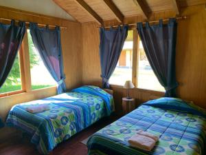 Los Coihues Patagonia Lodge في La Junta: سريرين يجلسون في غرفة مع نوافذ