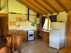 a kitchen with a white refrigerator and a table at Los Coihues Patagonia Lodge in La Junta
