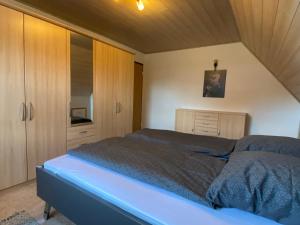 a bedroom with a large bed and wooden cabinets at Charmantes Ferienhaus Gernrode/ Harz, Balkon, Grill, 2 Schlafzimmer in Quedlinburg