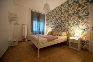 Casa Vacanze Partenope في نابولي: غرفة نوم بسرير وورق جدران استوائي