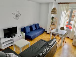 un salon avec un canapé bleu et une télévision dans l'établissement Apartamento La Caridad, à La Caridad