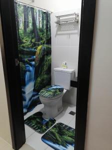 a bathroom with a toilet with a forest shower curtain at Fast Wifi 400 Mbps at Kasara Urban Resort Residences with Netflix and Pool Access in Manila