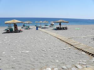 a sandy beach with umbrellas and people on the beach at Megim Hotel in Palaiochora