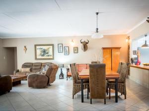 Bosveld Villa في مارلوث بارك: غرفة معيشة مع طاولة وكراسي