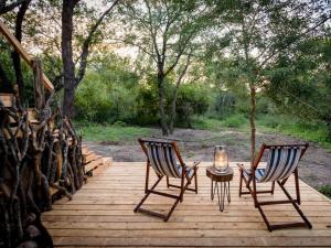 two chairs and a table on a wooden deck at Bosveld Villa in Marloth Park
