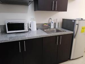 a kitchen with a sink and a microwave and a refrigerator at Fast Wifi 400 Mbps at Kasara Urban Resort Residences with Netflix and Pool Access in Manila
