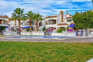 a group of houses with palm trees and a pool at Pool View Apartment at Jumilla III in Playa Flamenca