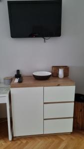 un televisor en la parte superior de un tocador blanco con un tazón en él en Apartman Lumi, en Čakovec