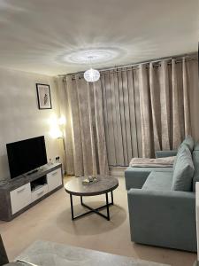 a living room with a couch and a tv and a table at stylish luxe apartment in Harlow