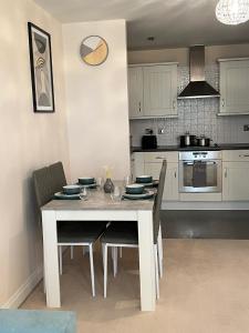 a kitchen with a white table and chairs and a kitchen with a stove at stylish luxe apartment in Harlow