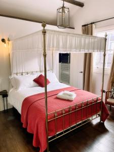 una camera con letto a baldacchino e coperta rossa di Maids Guest Rooms a Kew