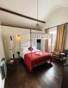 um quarto com uma cama de dossel e um cobertor vermelho em Maids Guest Rooms em Kew