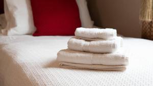 tre asciugamani impilati sopra un letto di Maids Guest Rooms a Kew