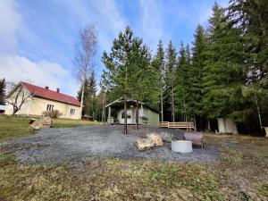 a yard with a house and a bench and trees at Satukurki-vierasmaja - Simple and Cute Cabin in Sastamala