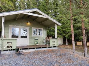 a green tiny house with a porch and two chairs at Satukurki-vierasmaja - Simple and Cute Cabin in Sastamala