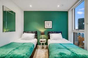 two beds in a room with a green wall at Contemporary and Stylish 2 Bed in Nine Elms in London