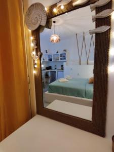 a mirror reflecting a bedroom with a bed and a kitchen at Litus Studios in Megas Yialos-Nites