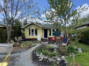 a garden in front of a yellow house at Beaver Lake Resort Site #36 in Lake Cowichan