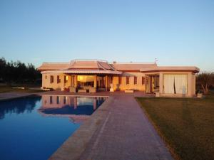 une maison avec une piscine en face de celle-ci dans l'établissement Domaine Lamrah, à Marrakech
