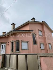 uma casa cor-de-rosa com uma vedação à frente. em Casa Ramos na Póvoa do Varzim