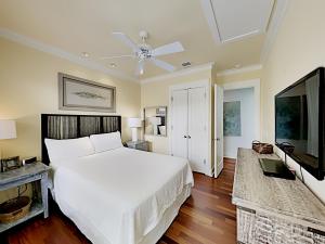 a bedroom with a white bed and a flat screen tv at Watercolor Whimsea in Seagrove Beach