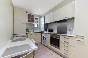 a kitchen with white cabinets and a white counter top at Spacious 2 Bedroom Apartment in Ealing Broadway in Ealing