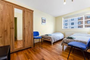 イーリングにあるSpacious 2 Bedroom Apartment in Ealing Broadwayのベッドルーム1室(ベッド1台、青い椅子2脚付)