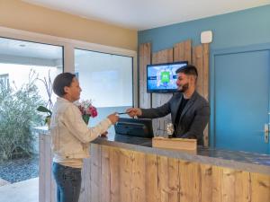 a man and a woman standing at a counter at ibis Styles Marennes d'Oléron in Marennes