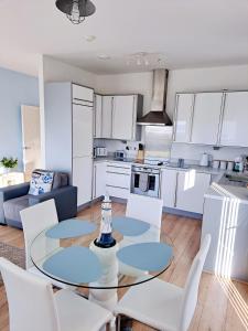 a kitchen and living room with a glass table and chairs at Coastal apartment with beach on your doorstep! in Llanelli