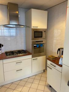 a kitchen with white cabinets and a microwave at Bed&Bulbs in Hillegom