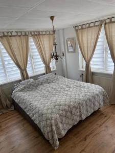 a bedroom with a bed and two windows at Bed&Bulbs in Hillegom