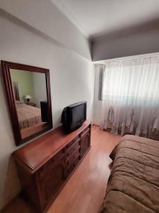 1 dormitorio con espejo, 1 cama y TV en Torre Jacarandá de Buenos Aires en Buenos Aires
